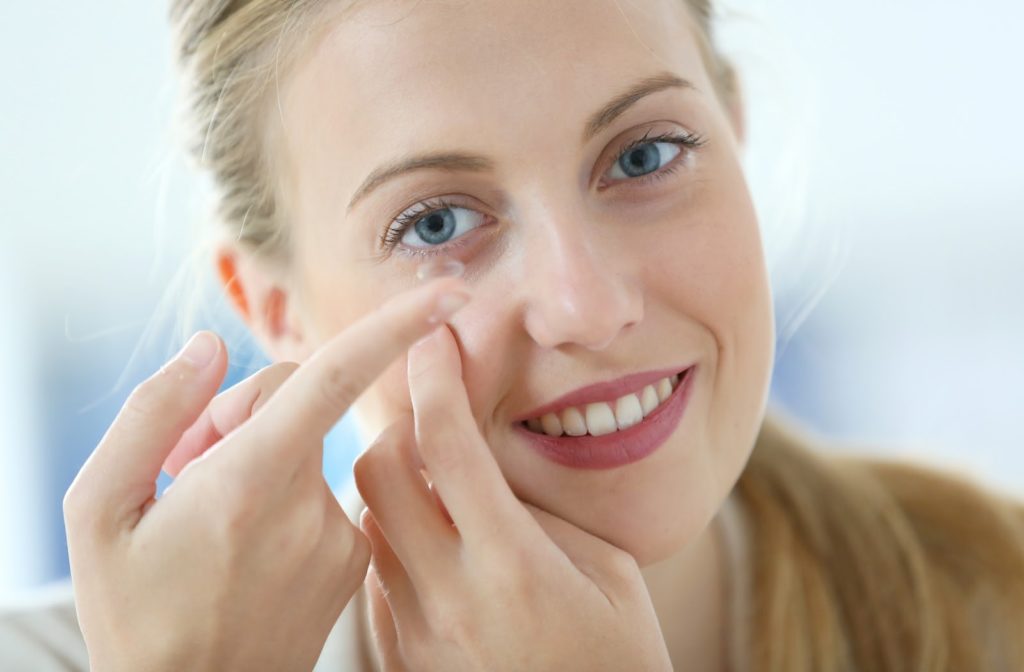 Young happy woman putting in contact lenses to control myopia