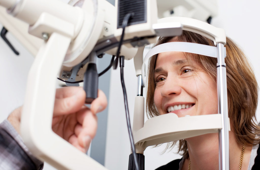 Optometrist examining happy woman's eyes at office.