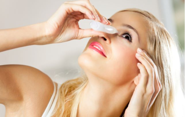 Young women looking up while putting in eye drops for dry eyes