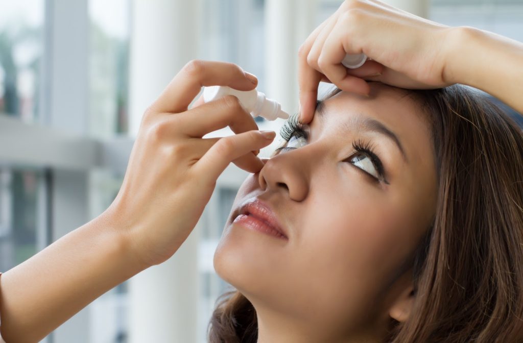 Women putting in eye drops in to her eyes due to dry eyes