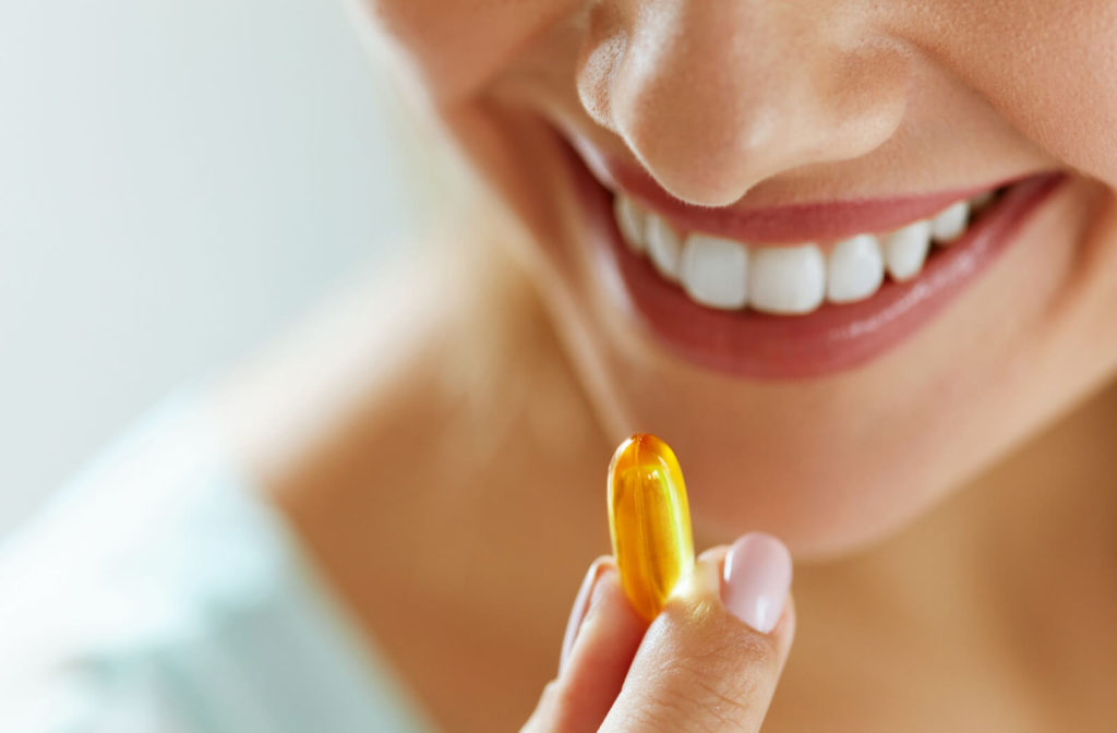 A young woman is taking omega-3 supplements.