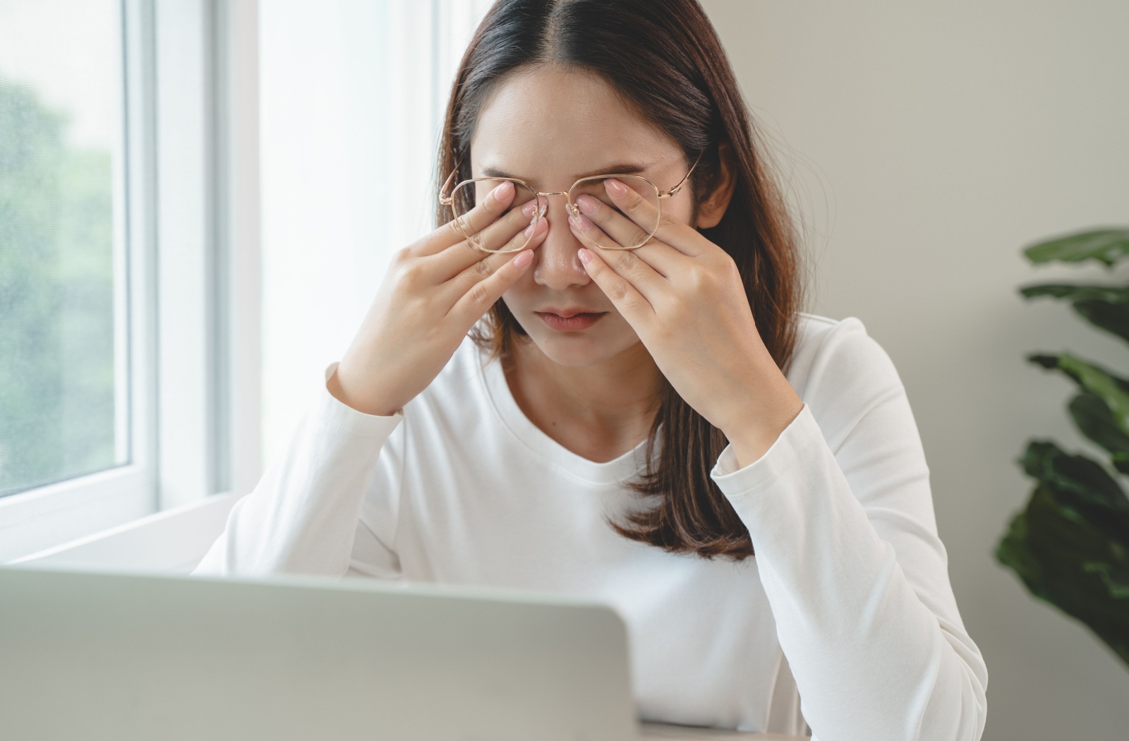 Woman rubbing her dry eyes in front of her laptop.