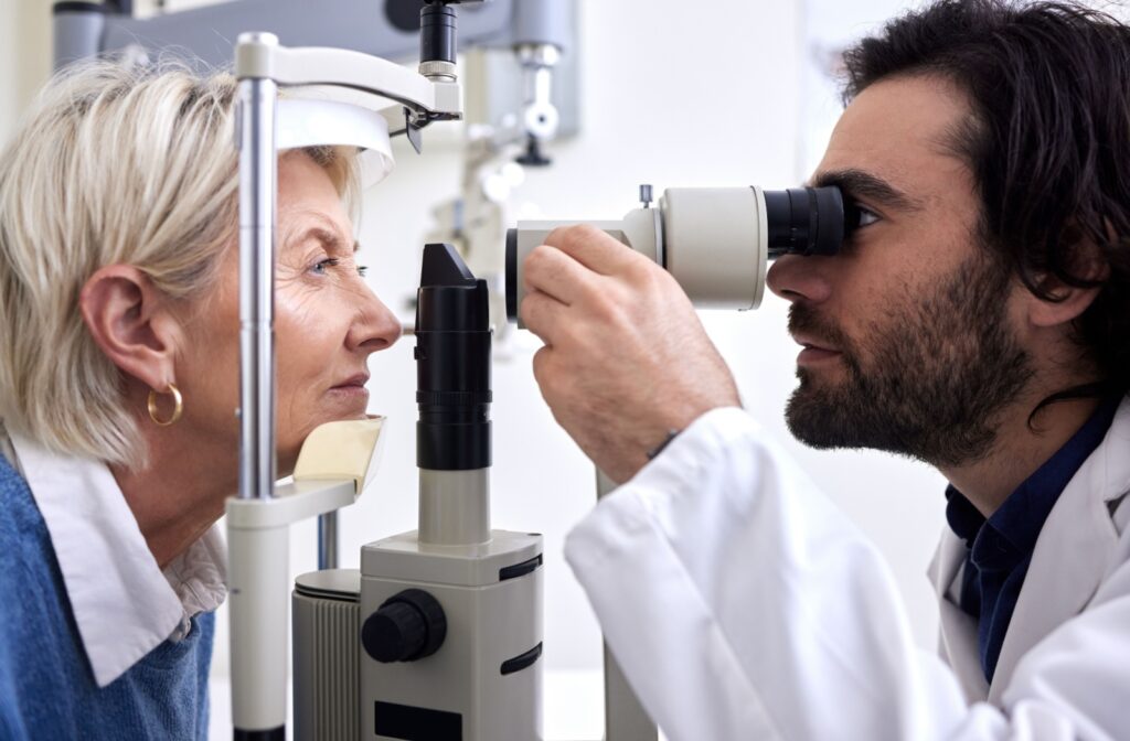 A side view of an optometrist carefully examining an older patient's eyes to find the cause of their worsened eyesight.