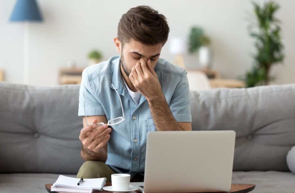 A young professional rubs their tired and sore eyes after spending a long time on the computer.
