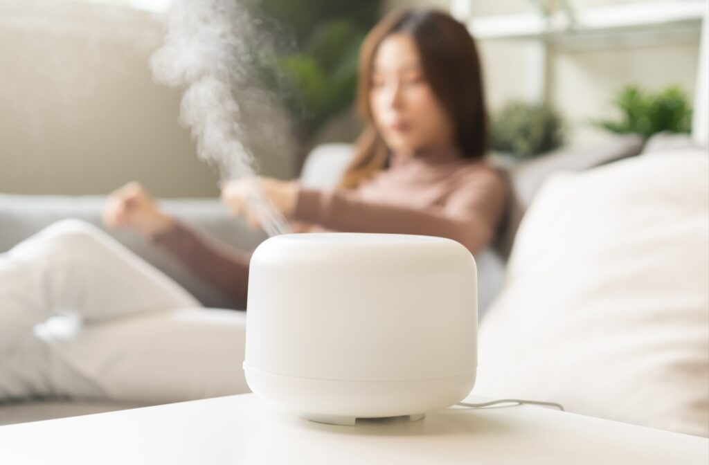Close up of a white humidifier pushing out air with a woman sitting on a couch in the background