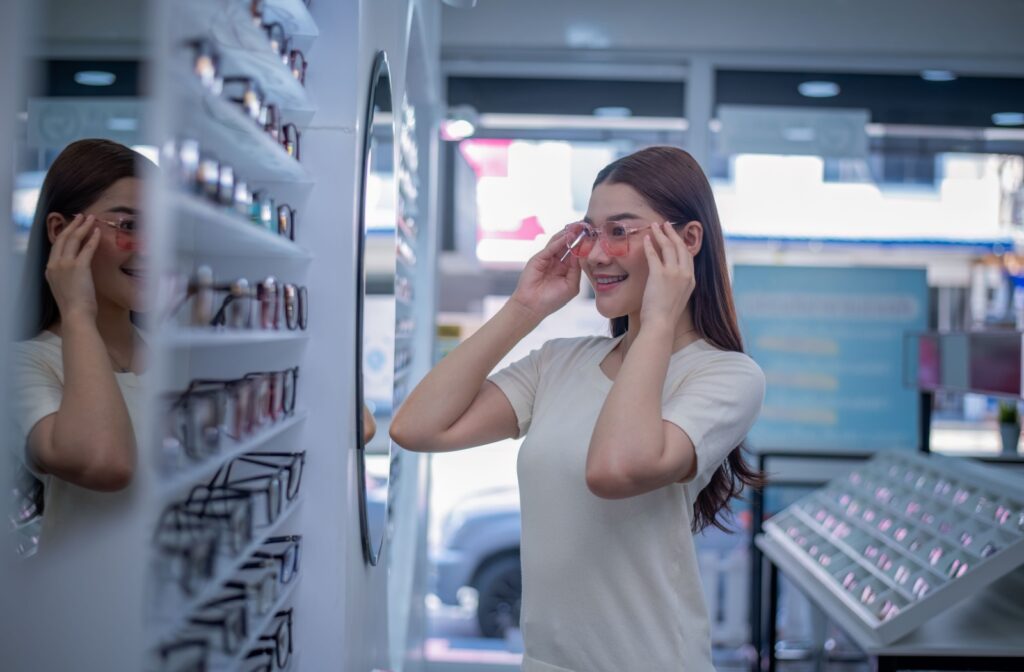 A person trying on a pink pair of glasses at an optometrists